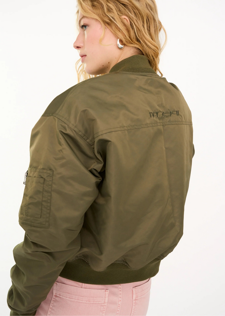 Person wearing a green jacket with a brand logo on a white background