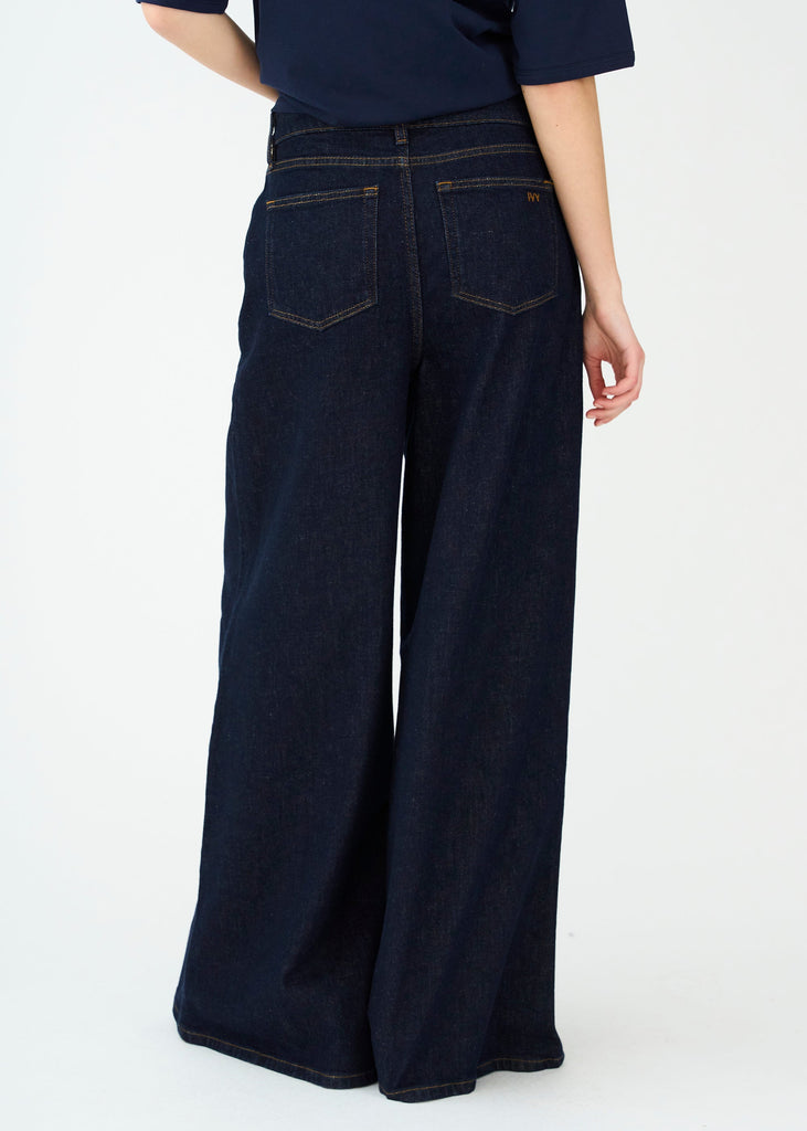 Person wearing dark blue wide-leg jeans on a white background