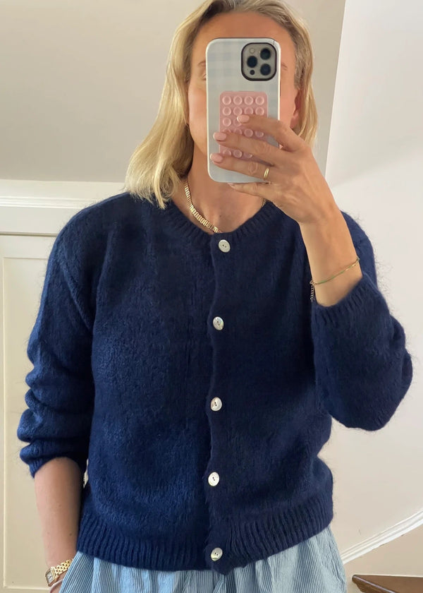 Person wearing a blue cardigan taking a mirror selfie.