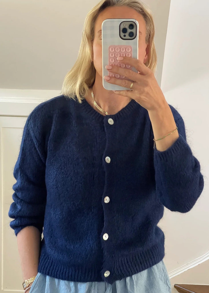 Person wearing a blue cardigan taking a mirror selfie.