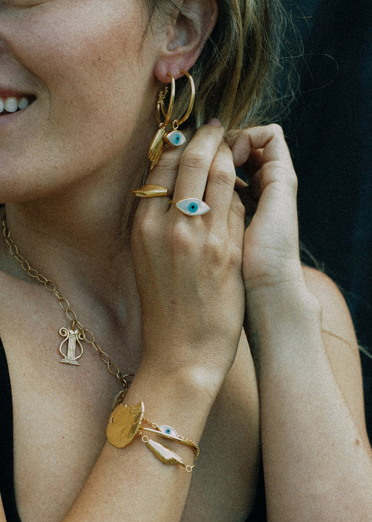 Close-up of a person wearing gold jewelry including earrings, necklace, and bracelet.