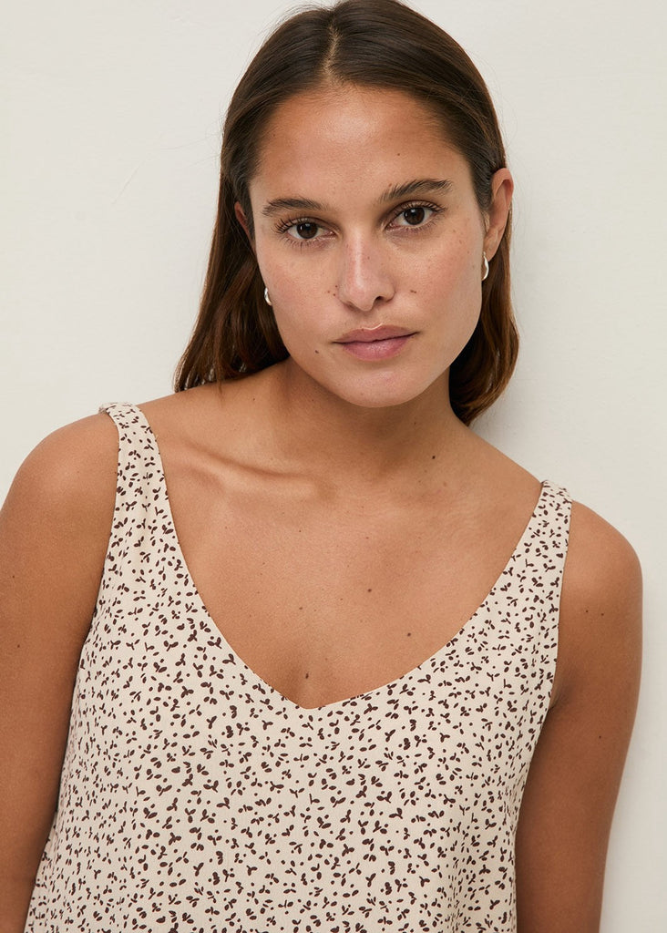 Woman wearing a patterned sleeveless top against a plain background