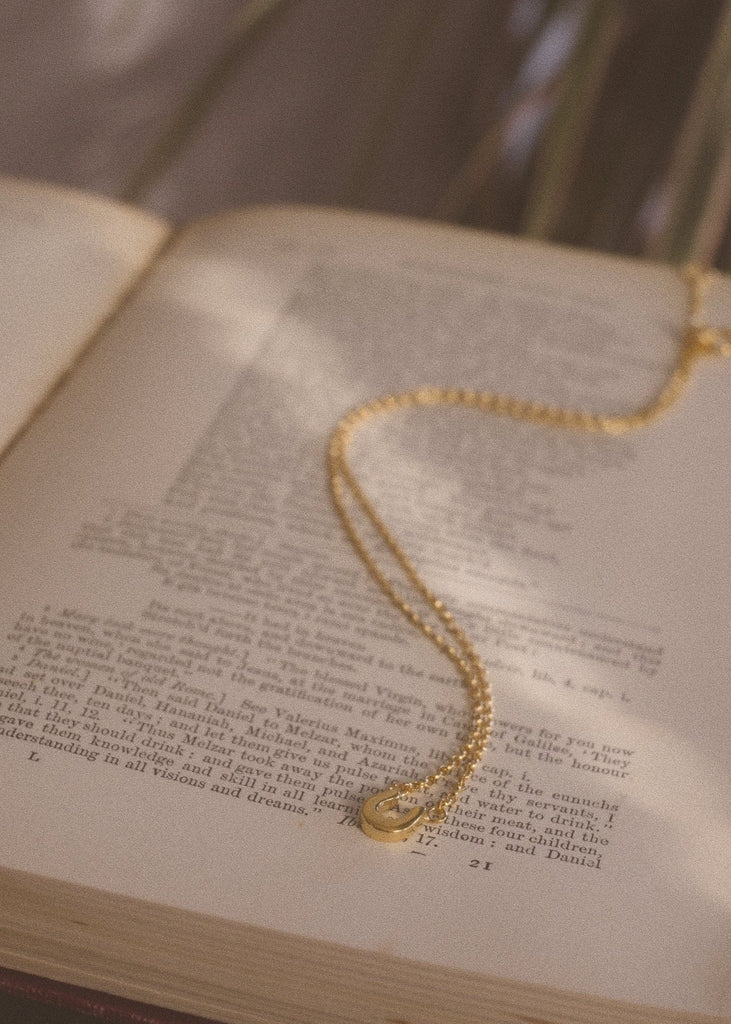 Gold necklace on an open book with a blurred background