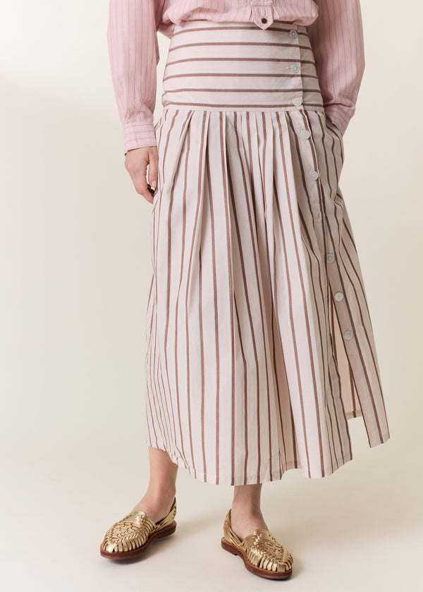 Person wearing a pink shirt and striped skirt on a plain background
