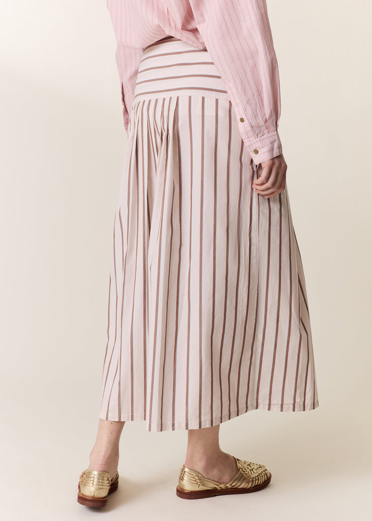 Person wearing a pink striped skirt and pink shirt on a plain background