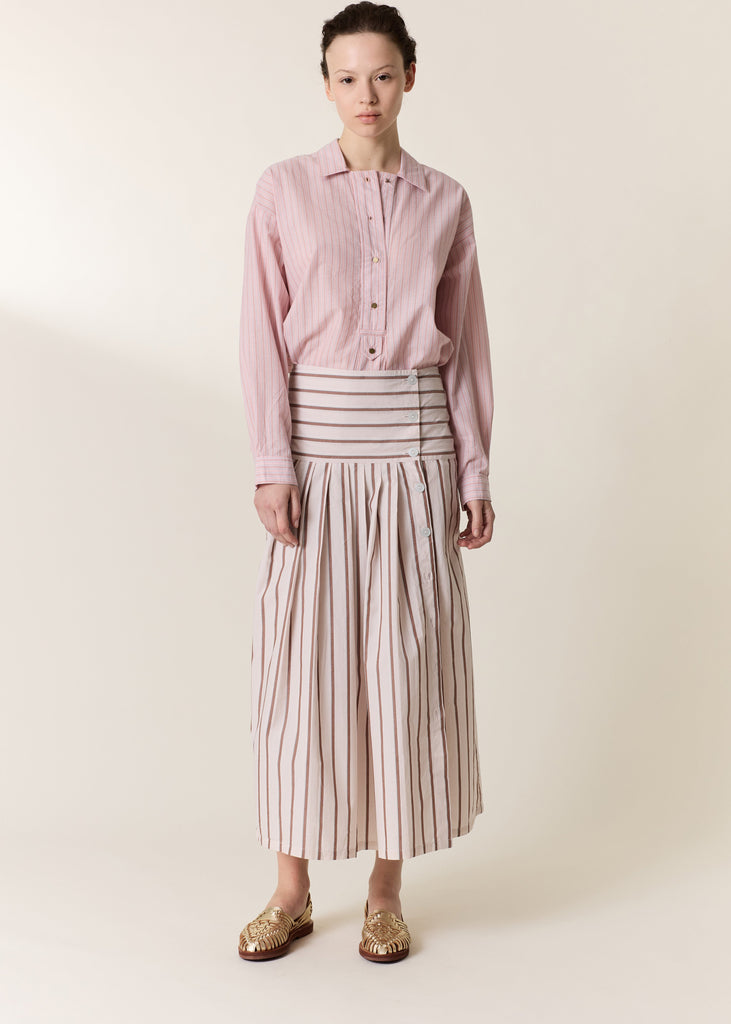 Person wearing a pink shirt and striped skirt on a plain background