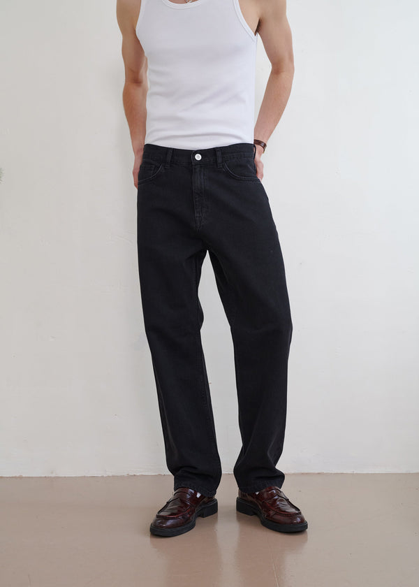 Person wearing black pants and a white tank top against a plain background