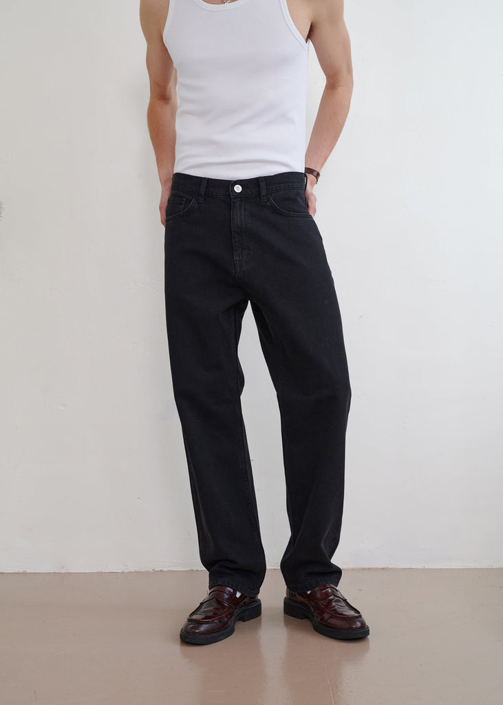 Person wearing black pants and a white tank top against a plain background