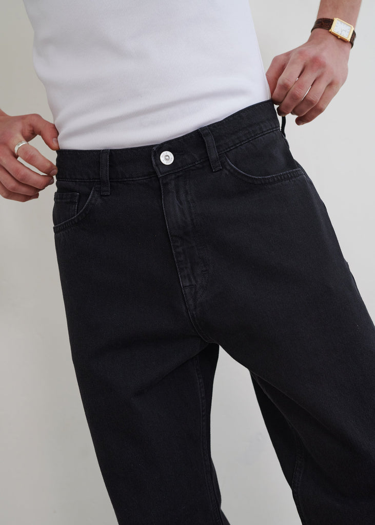 Person wearing black jeans and a white shirt against a plain background