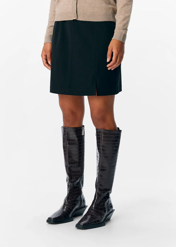 Person wearing black knee-high boots on a white background