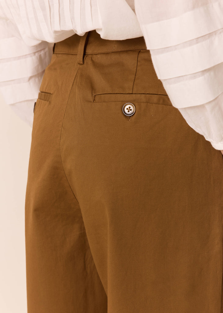 Brown pants with a white shirt underneath on a beige background