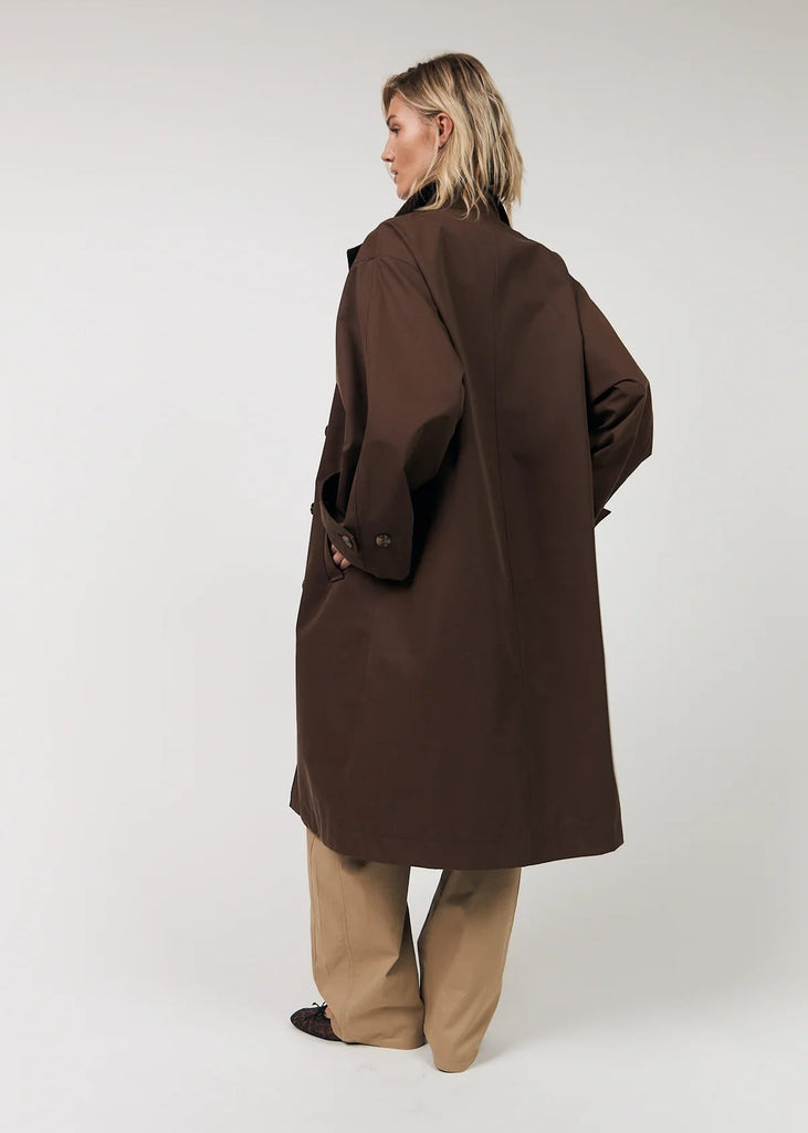 Person wearing a brown coat on a white background