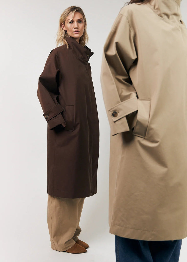 Two people wearing long coats, one brown and one beige, on a white background.