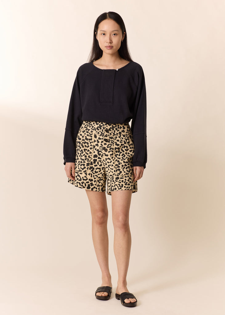 Woman wearing a black top and leopard print shorts on a beige background