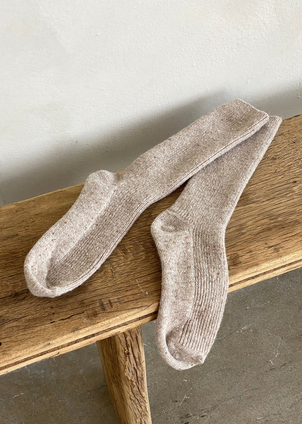 Pair of beige socks on a wooden surface with a neutral background