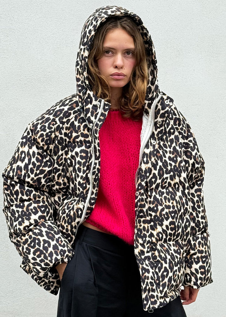 Person wearing a leopard print jacket over a pink top against a light gray background