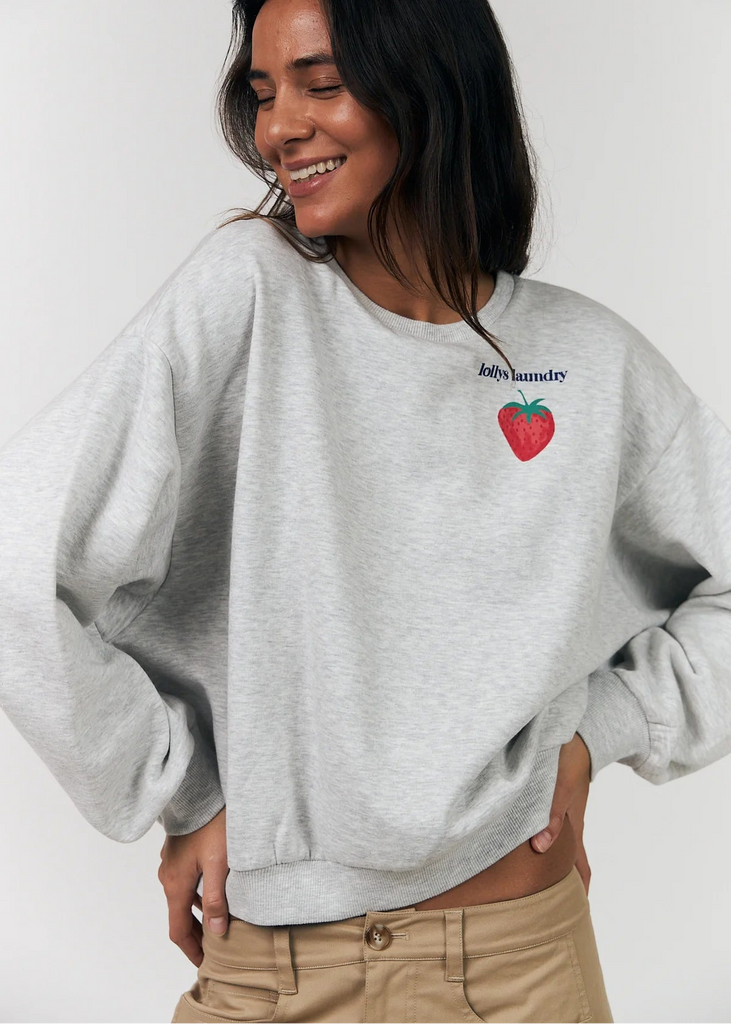 Person wearing a gray sweatshirt with a red heart design and text on a plain background