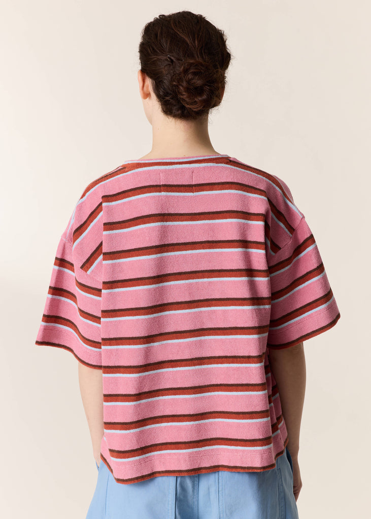 Person wearing a pink and brown striped shirt with a plain background