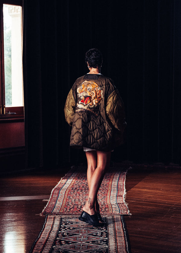 Person wearing a jacket with a tiger design in a dimly lit room.
