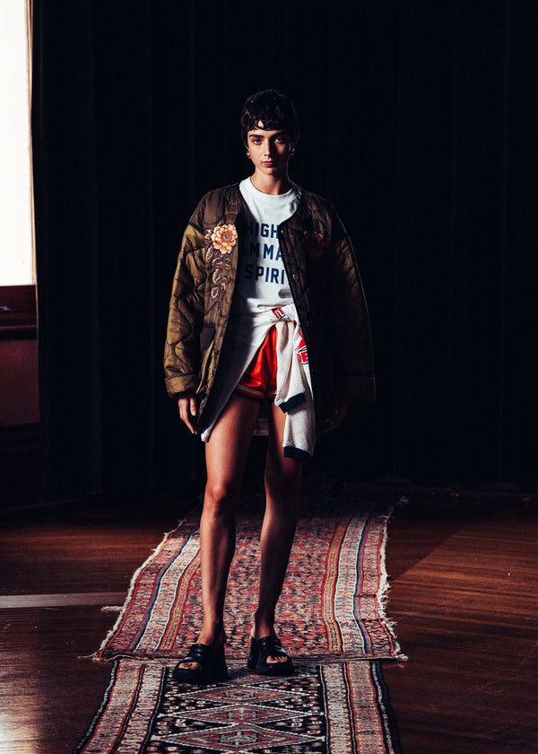 Person standing on a patterned rug in a dimly lit room