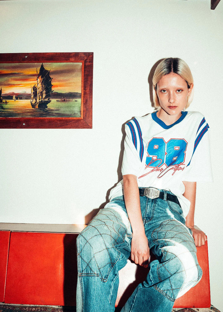 Person wearing a sports jersey with the number 88 sitting on a red couch.