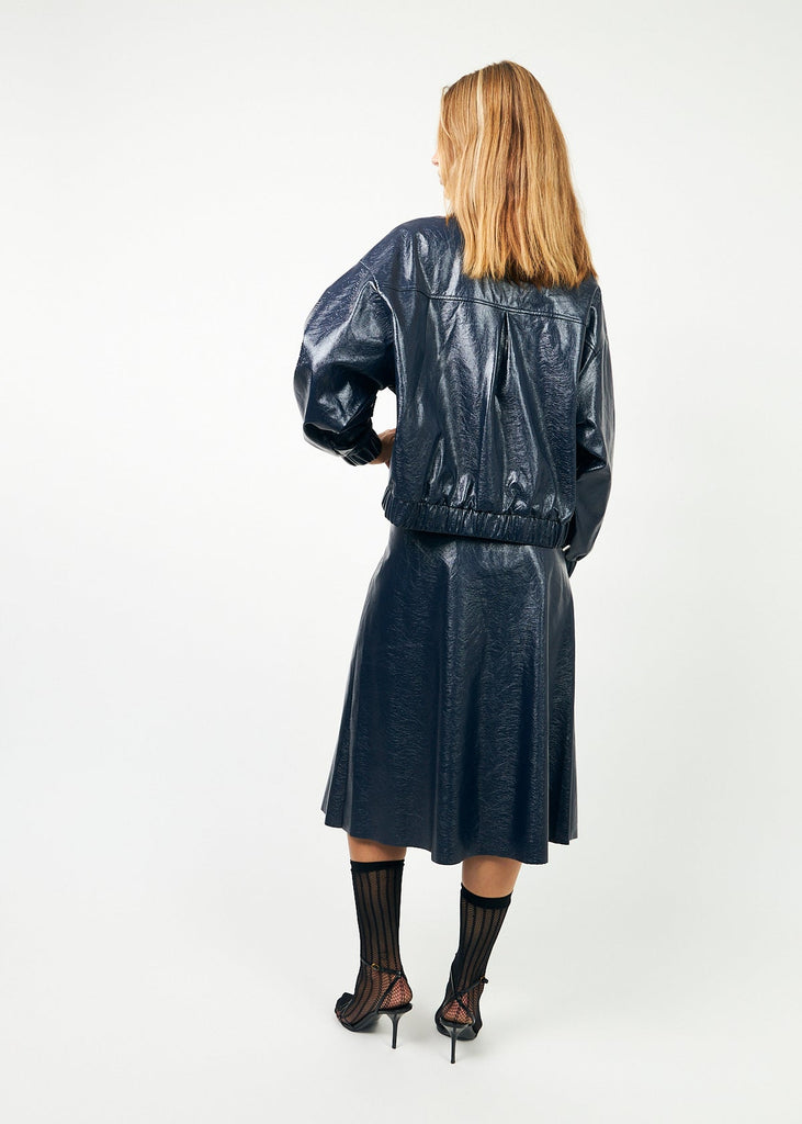 Person wearing a black leather jacket and skirt set on a white background