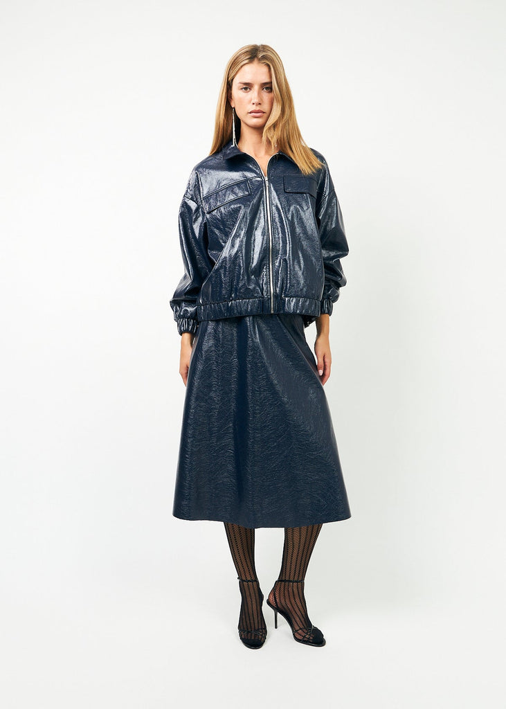 Woman wearing a black vinyl jacket and skirt on a white background