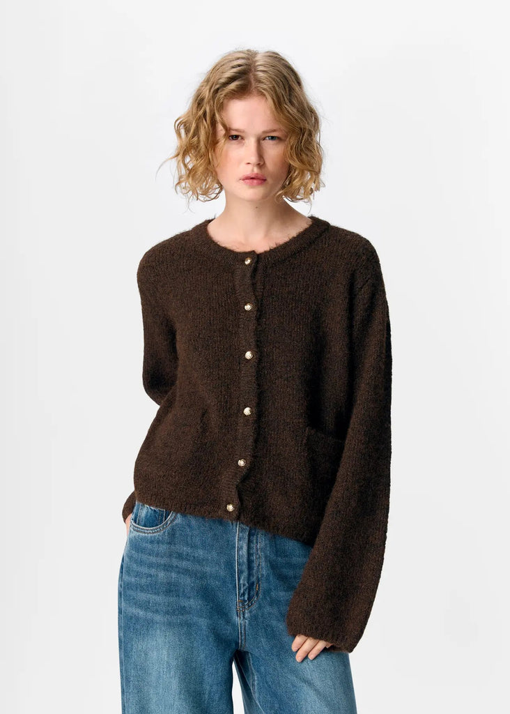 Woman wearing a brown cardigan and blue jeans on a white background