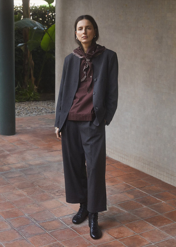 Woman in a stylish outfit standing on a tiled patio.