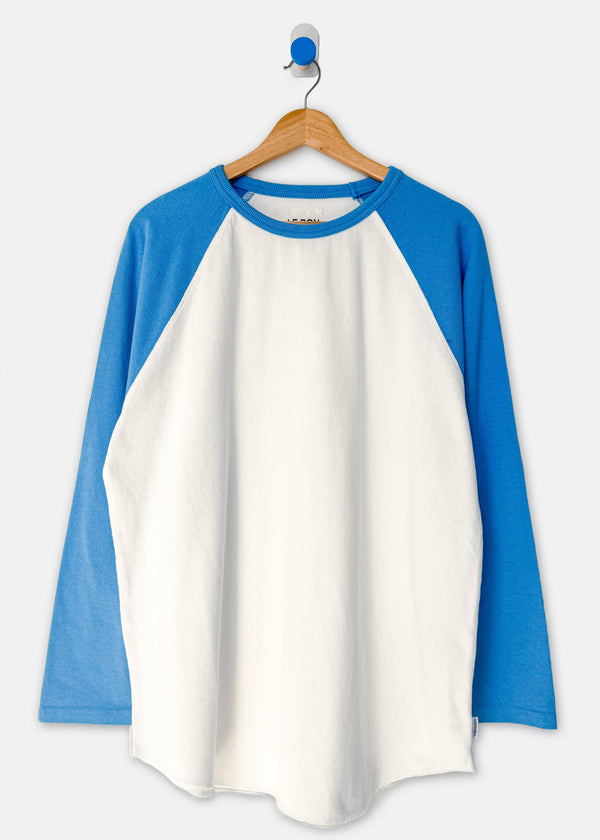 A raglan-style long-sleeve shirt hanging on a wooden hanger against a light gray background. The shirt has a white body and bright blue sleeves and collar.