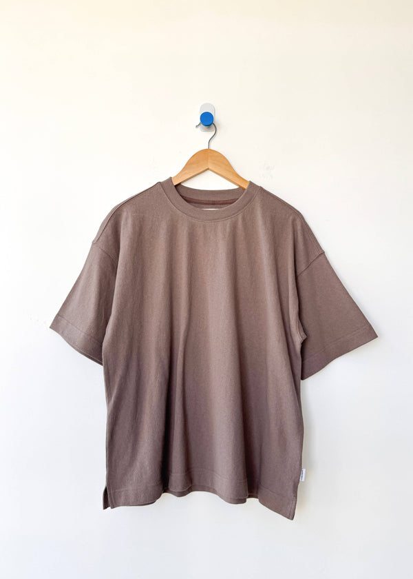 Brown t-shirt on a wooden hanger against a white background