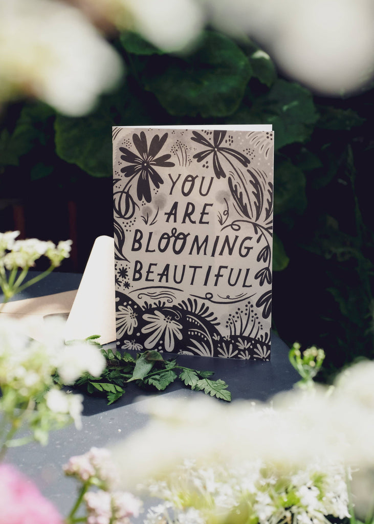 Decorative sign with 'You are blooming beautiful' text surrounded by flowers