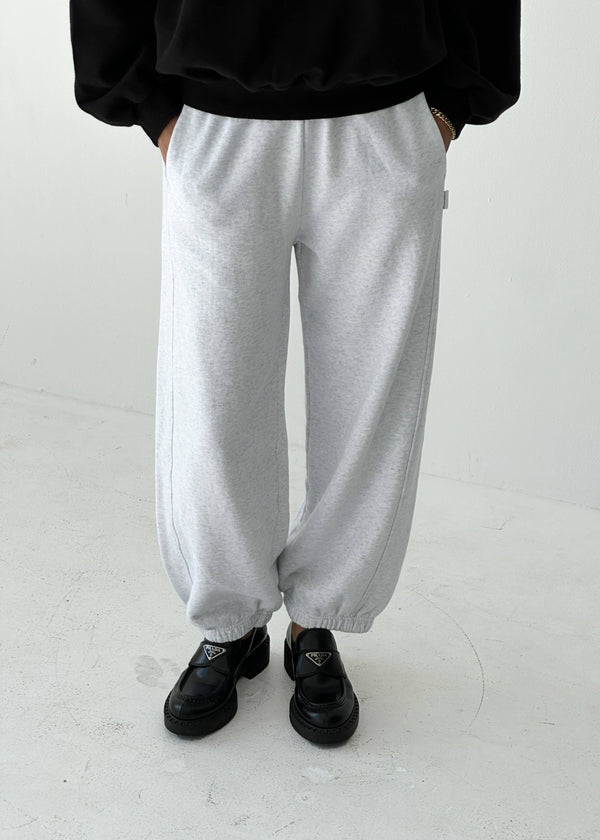 Person wearing gray sweatpants and black shoes on a white background