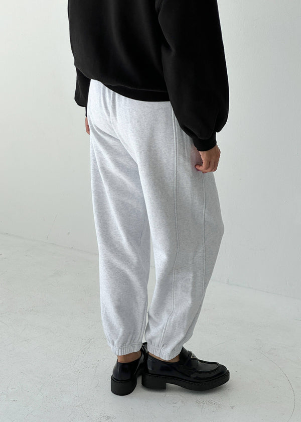 Person wearing a black sweatshirt and gray sweatpants on a white background