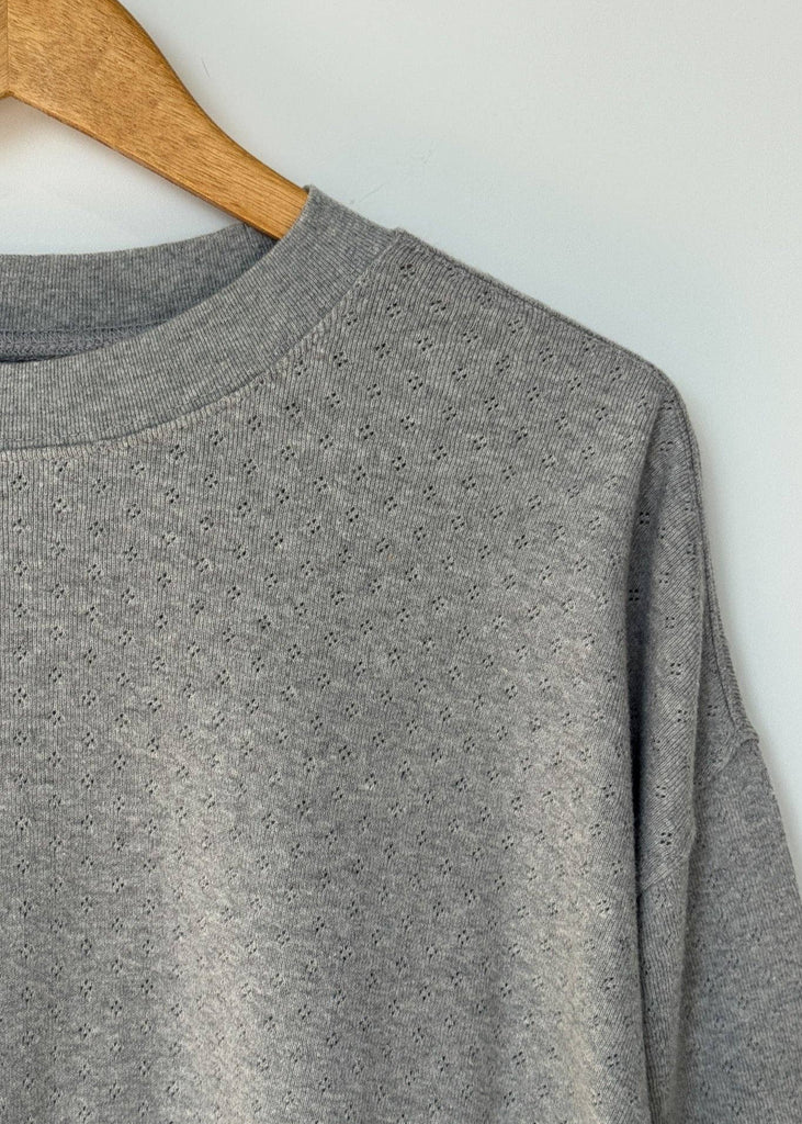 Gray sweatshirt on a wooden hanger against a light gray background