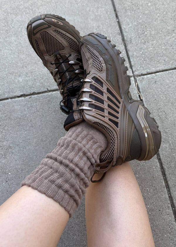 Person wearing brown shoes and socks on a gray pavement