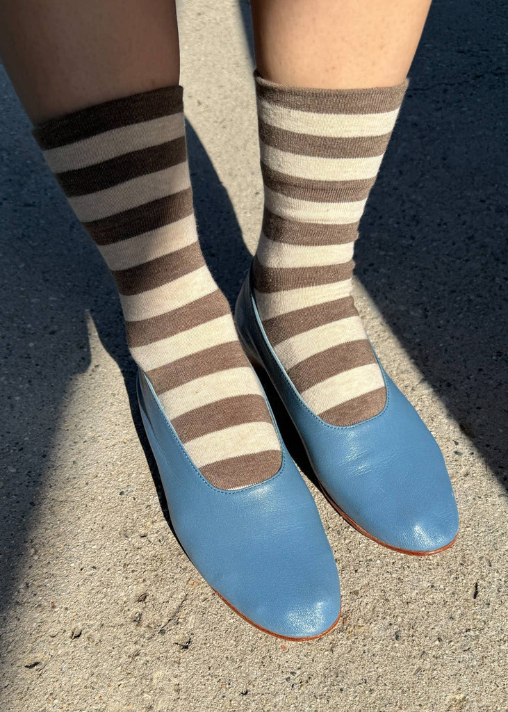 Striped socks and blue shoes on a concrete surface