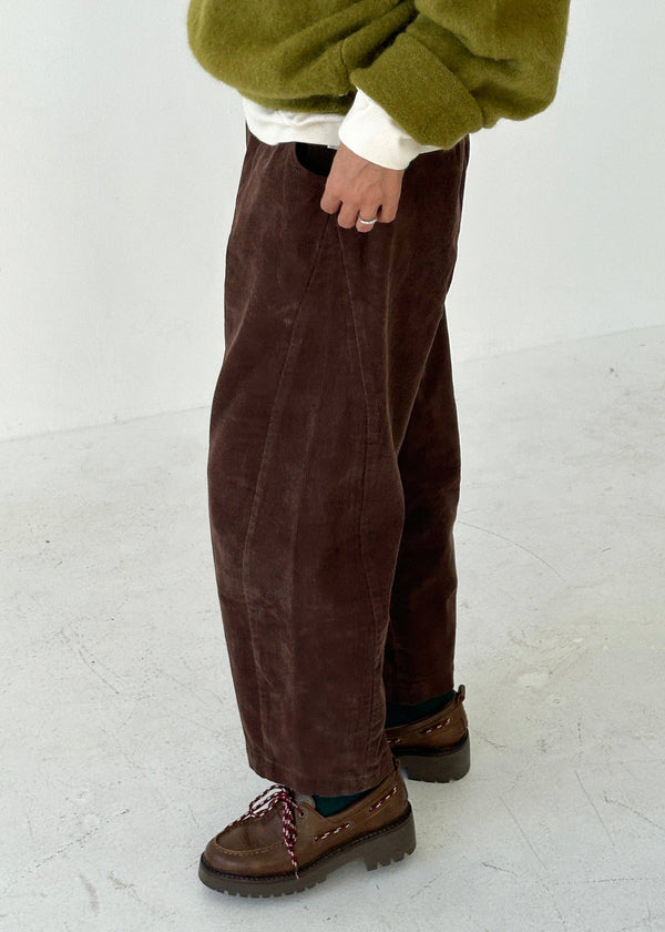 Person wearing brown corduroy pants and green sweater on a white background