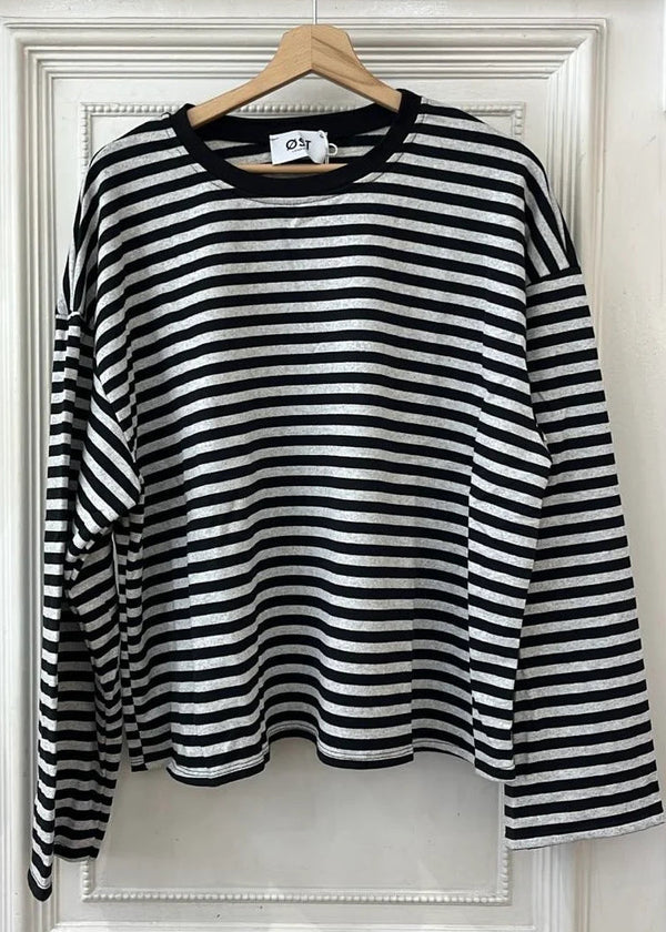 A black and white horizontally striped long-sleeve top hanging on a wooden hanger against a white paneled door.