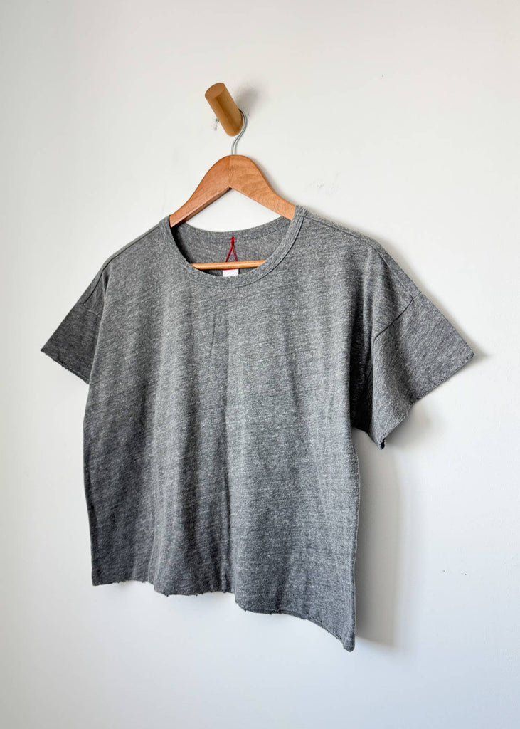 Gray t-shirt on a wooden hanger against a white background