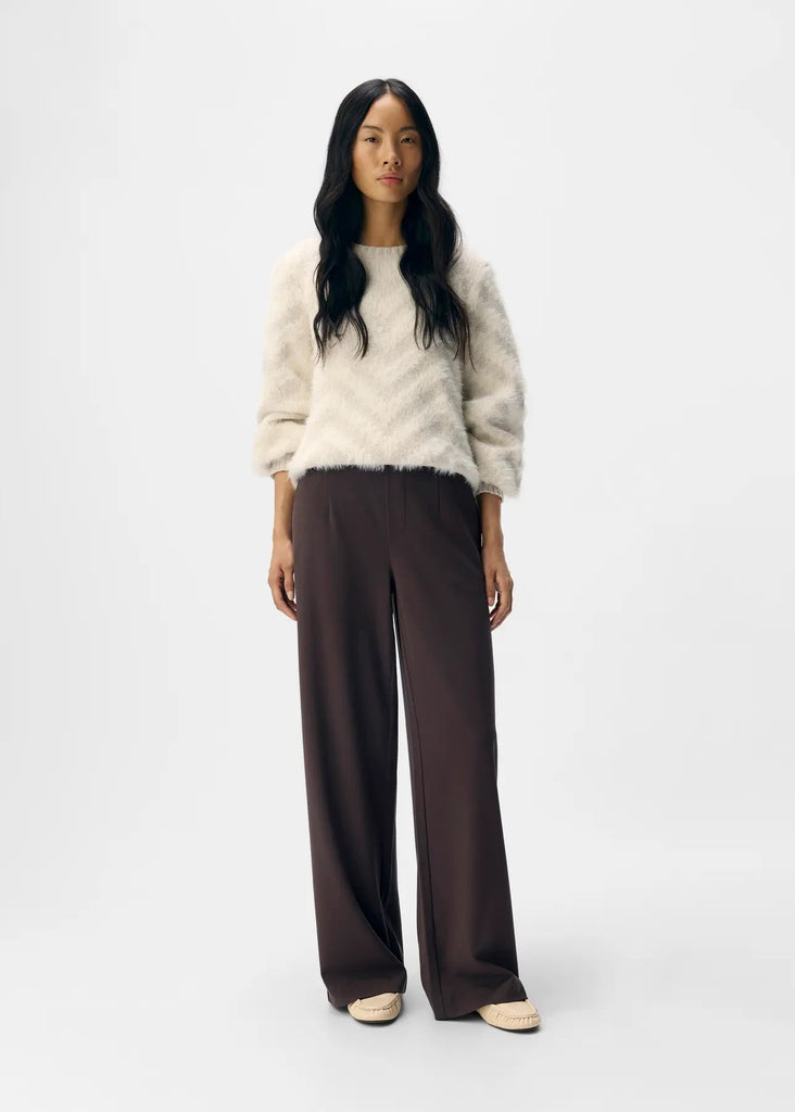 Woman wearing a white sweater and brown pants on a white background