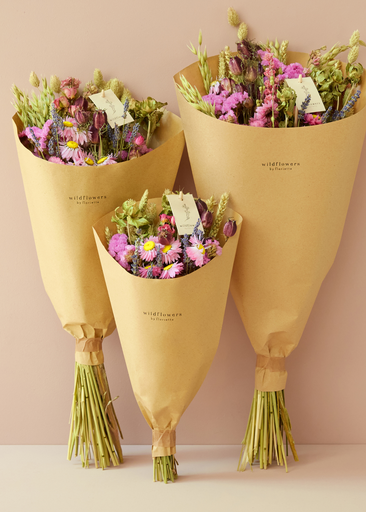 Three bouquets of flowers wrapped in yellow paper against a beige background