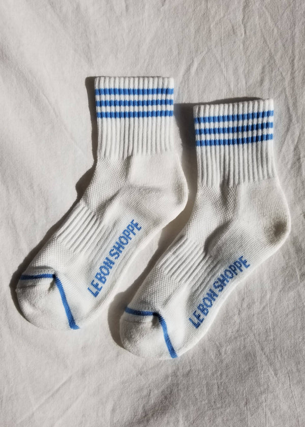 White socks with blue stripes and text on a textured surface