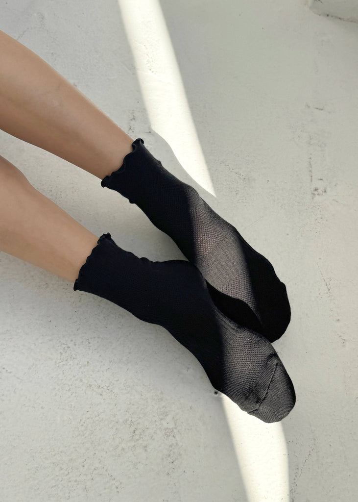 Black socks worn by a person on a light gray background