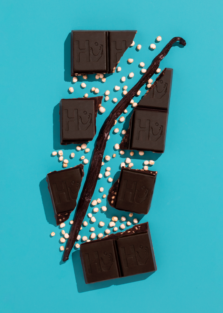 Dark chocolate bars with vanilla beans on a turquoise background