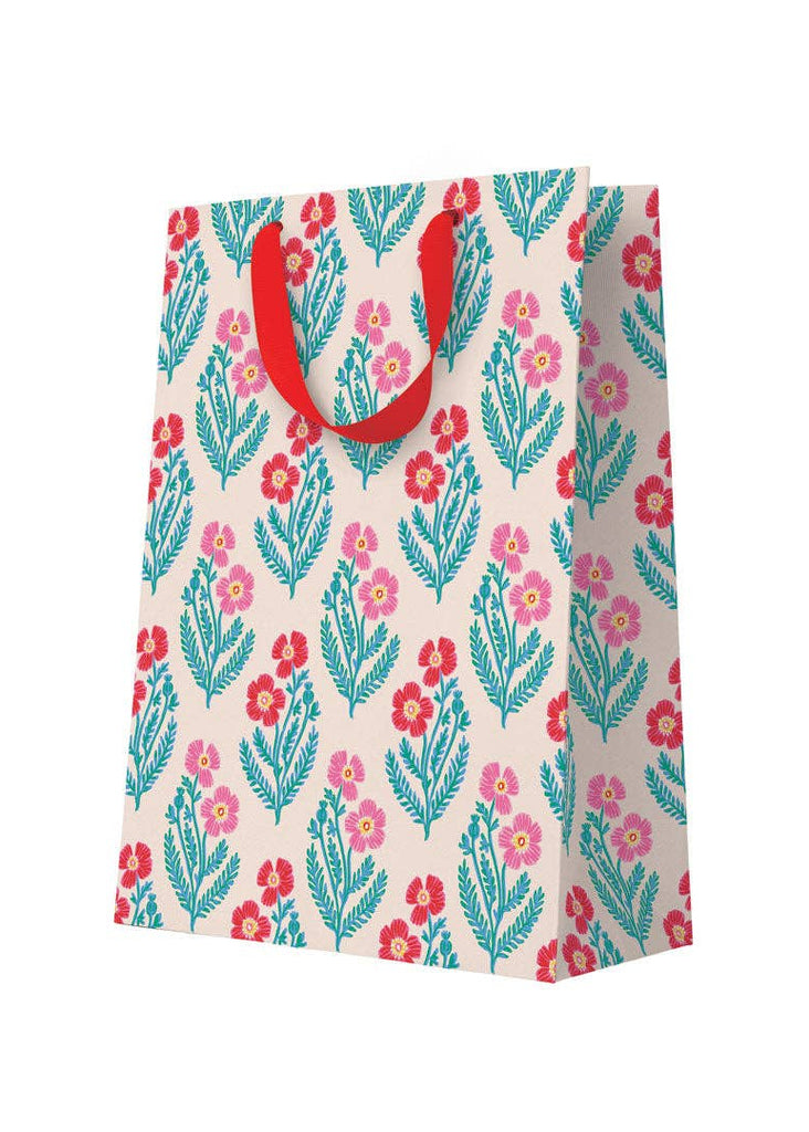 Floral patterned shopping bag with red handles on a white background