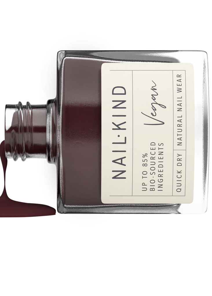 Nail polish bottle with dark red nail polish spilling out on a white background, featuring the brand 'NAILKIND'.