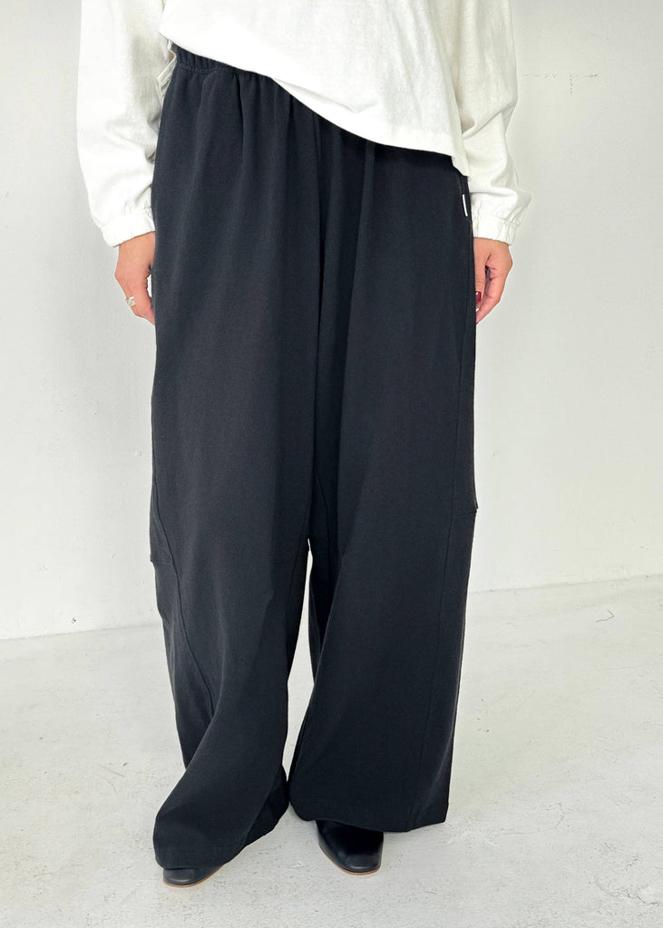 Person wearing a white shirt and black wide-leg pants on a white background