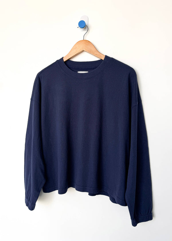 Navy blue sweatshirt on a wooden hanger against a white background