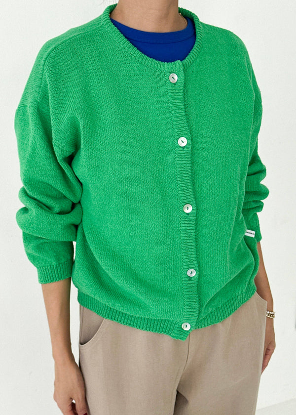 Green cardigan worn by a person on a white background